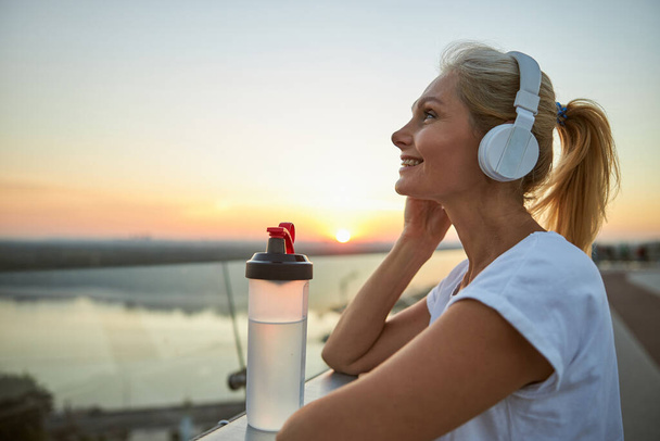 Joyous lady with a ponytail listening to music - Фото, зображення
