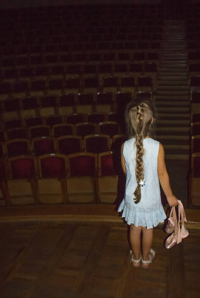 Ένα κοριτσάκι ονειρεύεται ένα χορευτικό μπαλέτο στη σκηνή. Έννοια της παιδικής ηλικίας. - Φωτογραφία, εικόνα