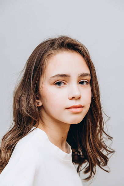 little pretty girl with expressive facial features posing for a photo on a gray background - Zdjęcie, obraz