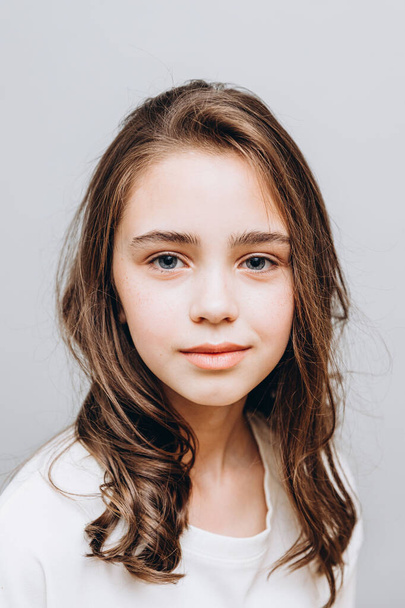 little pretty girl with expressive facial features posing for a photo on a gray background - Фото, зображення