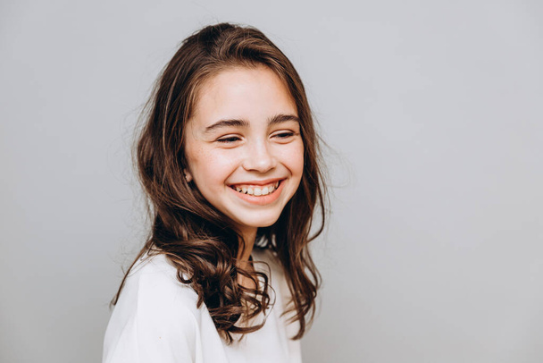 little pretty girl with expressive facial features posing for a photo on a gray background - Photo, Image