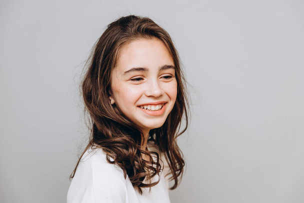 little pretty girl with expressive facial features posing for a photo on a gray background - Fotó, kép