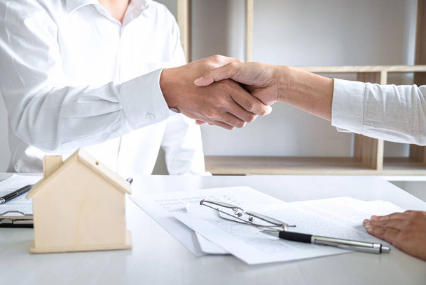 Real estate agent and customers shaking hands together celebrating finished contract after signing about home insurance and investment loan, handshake and successful deal. - Фото, изображение