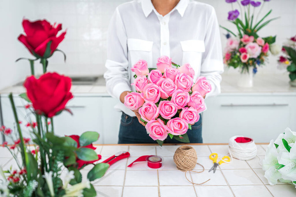 Arranging artificial flowers decoration at home, Young woman florist work making organizing diy artificial flower, craft and hand made concept. - Photo, image