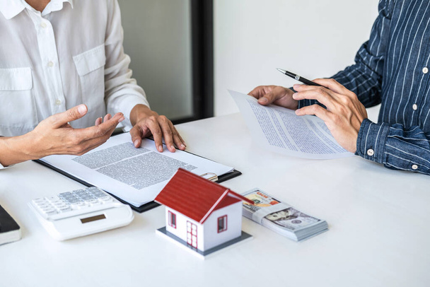 Real estate broker agent presenting and consult to customer to decision making sign insurance form agreement, home model, concerning mortgage loan offer for and house insurance. - Photo, image