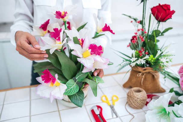 Arranging artificial flowers decoration at home, Young woman florist work making organizing diy artificial flower, craft and hand made concept. - Фото, зображення