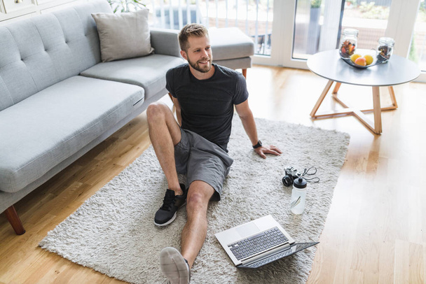 Handsome young man working out at home in the living room  - Fotografie, Obrázek
