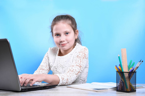 Retour à l'école .Happy mignon enfant industrieux est assis à un bureau à l'intérieur. Enfant apprend en classe à la maison avec ordinateur portable, ordinateur. - Photo, image