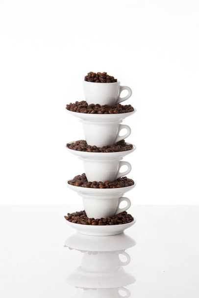 Куча из четырех кофейных чашек, наполненных кофе жареные бобы - Фото, изображение