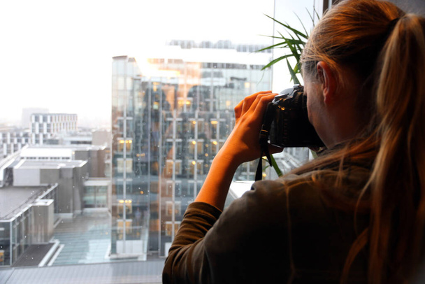 A young woman photographs the view of glass buildings in Brussels - Foto, imagen