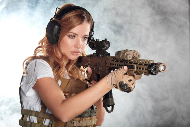 Портрет красивої жінки-воїна зі зброєю в димну ніч
 - Фото, зображення