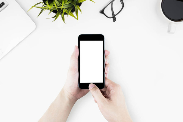 Hand houdt smartphone over witte bureau tafel met sup - Foto, afbeelding