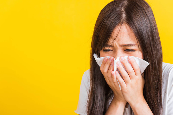 Portrait of Asian beautiful young woman sad she crying wipe the mucus with tissue, Close up of pretty girl sneezing sinus using towel to wipe snot from nose, studio shot isolated on yellow background - Foto, Bild