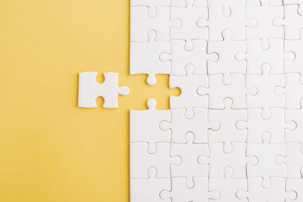 Top view flat lay of paper plain white jigsaw puzzle game texture last pieces for solve and place, studio shot on a yellow background, quiz calculation concept - Foto, afbeelding