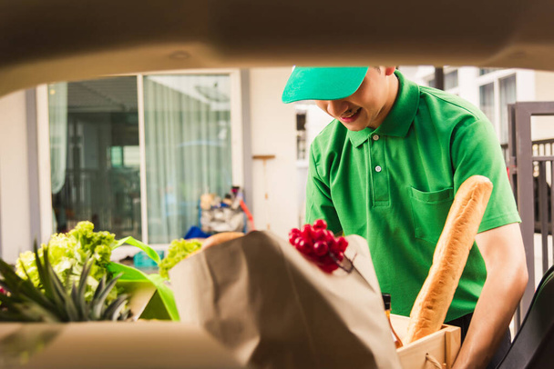Asian delivery man grocery prepare service giving fresh vegetables food and fruit full in wooden basket on back car to send woman customer at door home after pandemic coronavirus, Back to new normal - 写真・画像