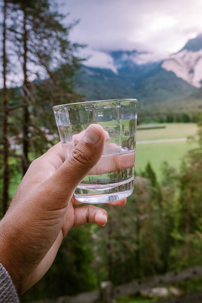 pohár víz a kézben, kilátással a hegyekre, ivóvíz  - Fotó, kép