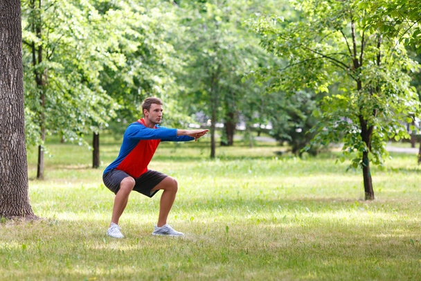 Workout outdoor. Waming up muscles in public park. - Valokuva, kuva
