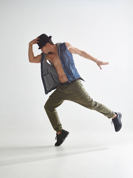 Cool young guy breakdancer in hat dancing hip-hop in studio isolated on white background. Break dance lessons - Foto, Imagem