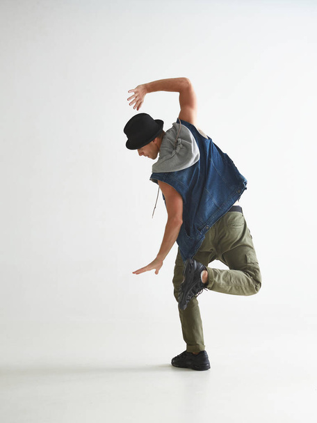 Cool guy breakdancer in hat dancing hip-hop in studio isolated on white background. Break dance lessons. View from back - Foto, Imagem