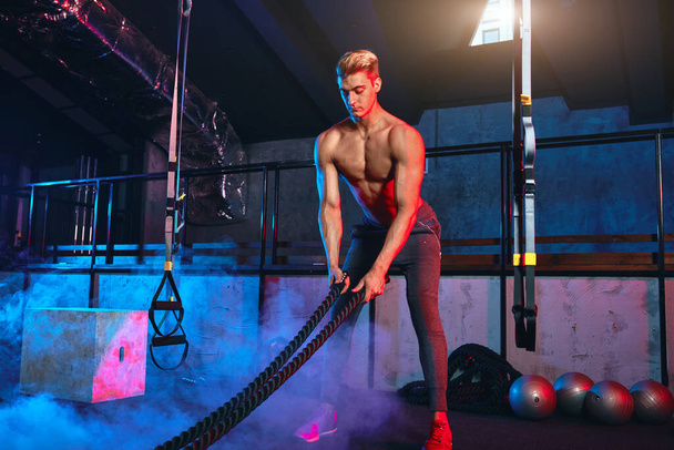 Muscular powerful man training with rope in functional training gym - Foto, Imagen