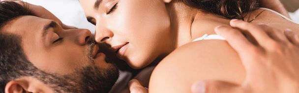 Concepto panorámico de hombre besando a mujer joven en la cama  - Foto, imagen