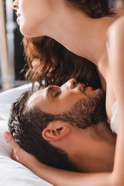 Focus selettivo della donna seducente che abbraccia l'uomo barbuto sul letto - Foto, immagini