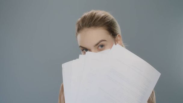 Mujer de negocios juguetona sosteniendo documentos en papel en el estudio. Profesional femenino - Foto, imagen