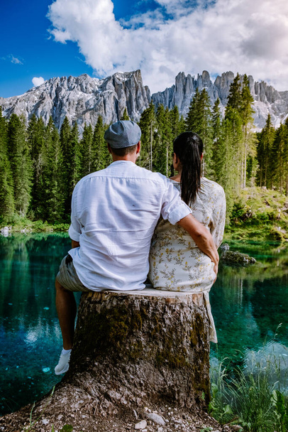 couple visit hte bleu lake in the dolomites Italy, Carezza lake Lago di Carezza, Karersee with Mount Latemar, Bolzano province, South tyrol, Italy. Landscape of Lake Carezza or Karersee and Dolomites - 写真・画像