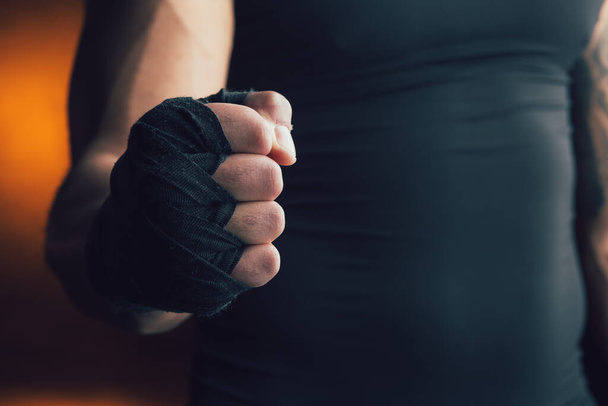 Cropped photo of a male fist clenched with a black boxing bandage on it - Фото, изображение
