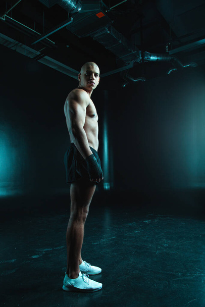 Handsome young muscular man looking into the distance while standing alone with boxing bandages on his hands - Foto, Bild