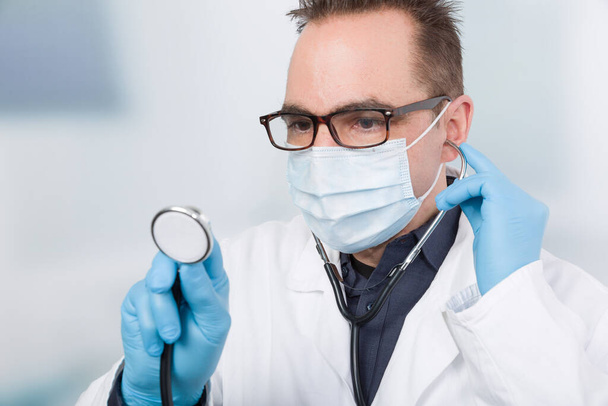 médico masculino frente a una sala de la clínica con un estetoscopio - Foto, imagen