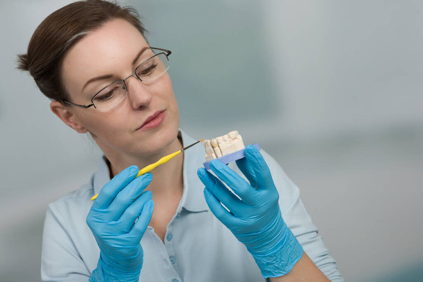 женщина-зубной техник работает над зубными частями в стоматологическом лабо - Фото, изображение
