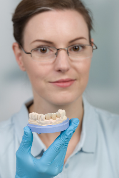 técnico dental femenino trabaja en piezas de prótesis dentales en un labio dental - Foto, imagen