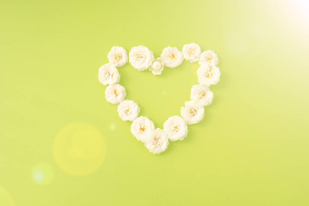 Flowers composition. heart frame of white small rose on green background. Mother's day, Valentine's day, birthday, spring, summer concept. Flat lay, top view, copy space - Photo, Image