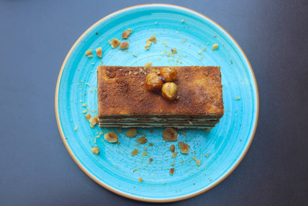 Delicious piece of cake with nuts on a blue plate. Top view. - Foto, Imagen