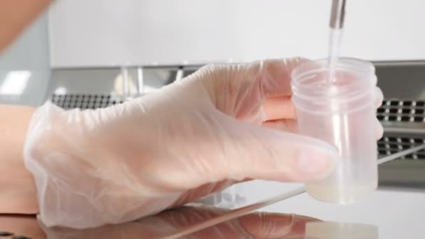 Egy közeli kép az orvosról, aki sperma mintával dolgozik. tudós embriológus spermát ad ki a tesztbankból elemzésre. Laboratóriumi dolgozó a modern mikrobiológiai szekrényben. 4 k videó - Felvétel, videó