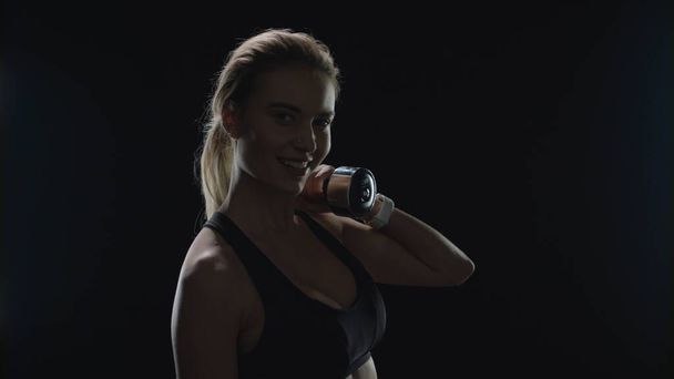 Urheilu nainen hymyilee käsipaino olkapäällä kuntosalilla. Fitness-malli hymyilee - Valokuva, kuva
