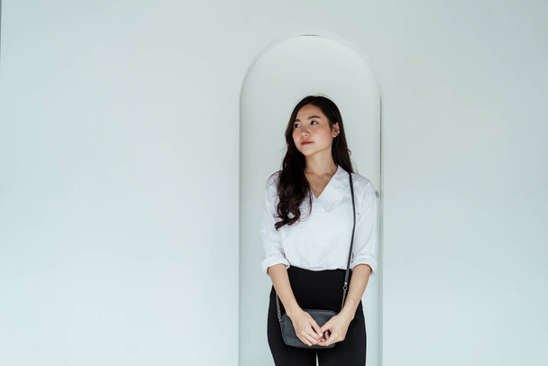 красива молода азіатська бізнес-леді на білій сорочці, що стоїть на білій стіні
. - Фото, зображення