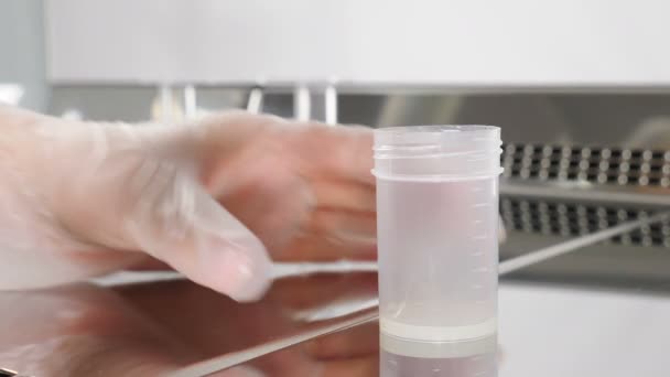 Laboratóriumi dolgozó a modern mikrobiológiai szekrényben. Egy közeli kép az orvosról, aki sperma mintával dolgozik. tudós embriológus spermát ad ki a tesztbankból elemzésre. 4 k videó - Felvétel, videó