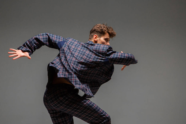 Stylish young guy dancer in suit dancing modern expressive dance in studio. Dance school poster. Dance lessons - Foto, imagen