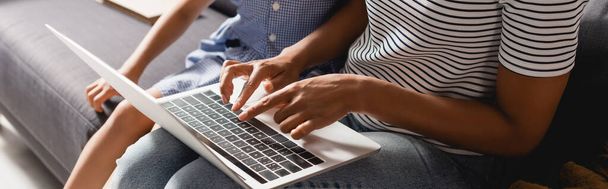 visão parcial do freelancer afro-americano trabalhando no laptop perto da filha, conceito panorâmico - Foto, Imagem