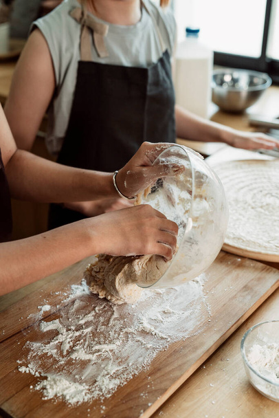 Asian baker woman let the dough out of glass bowl rest on the wooden plate. - Foto, imagen