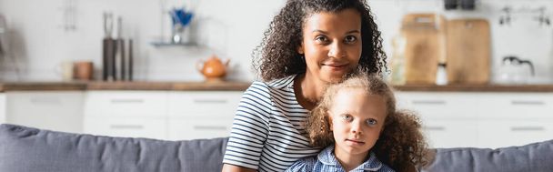 encabezado del sitio web de mamá afroamericana con hija mirando a la cámara mientras está sentado en la cocina - Foto, Imagen