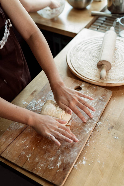 Konditorin knetet Brotteig auf Arbeitsplatte in der Küche. Kochen mit Mehl und Butter. Wie man Brotteig mit den Händen macht. Kochvorgang. - Foto, Bild