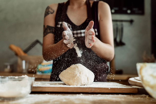 Asian pastry chef baker woman sprinkle flour on bread dough. Making bread procedures. Cooking scene. - Photo, image