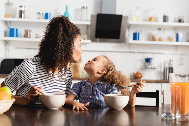 afro-americana mãe e filha fazendo rostos de pato enquanto olham um para o outro durante o café da manhã - Foto, Imagem