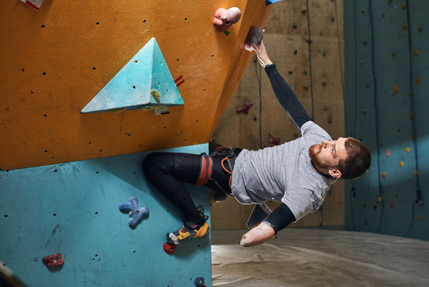 Physically handicapped sportsman starts climbing training in bouldering center - Photo, Image
