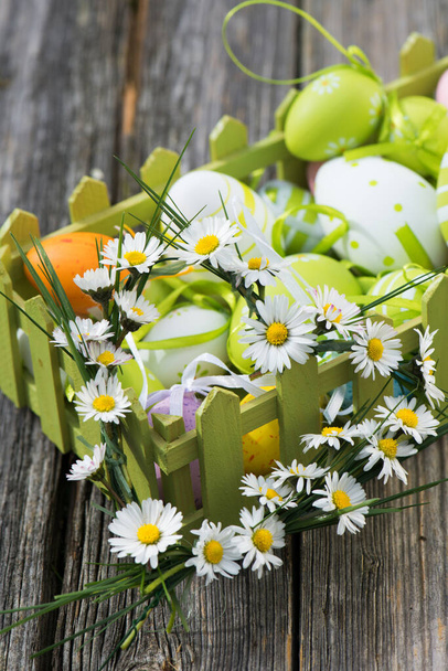 Colorful easter eggs with daisies on wood - Фото, зображення