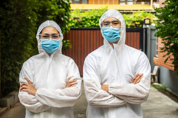 Asian doctor man and nurse woman wear PPE suit or Personal Protective Equipment and medical mask which use for protect covid-19 virus pandemic visiting patient at home for safety - Photo, Image