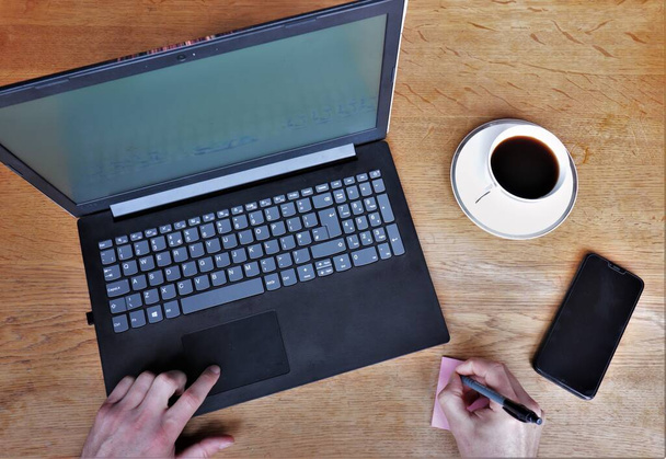 Вид на офисный стол с компьютером, телефоном и кофе. Руки показаны - Фото, изображение